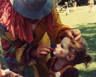 photo of clown applying clown makeup to child's face